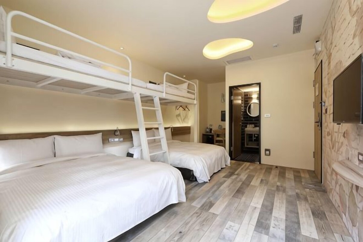 A room with bunk beds, a wooden floor, a stone wall, and a television.