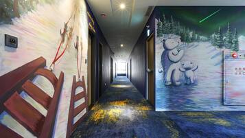 A hallway with a mural of a snowy landscape and bears, a wooden bench, and a fire alarm panel.