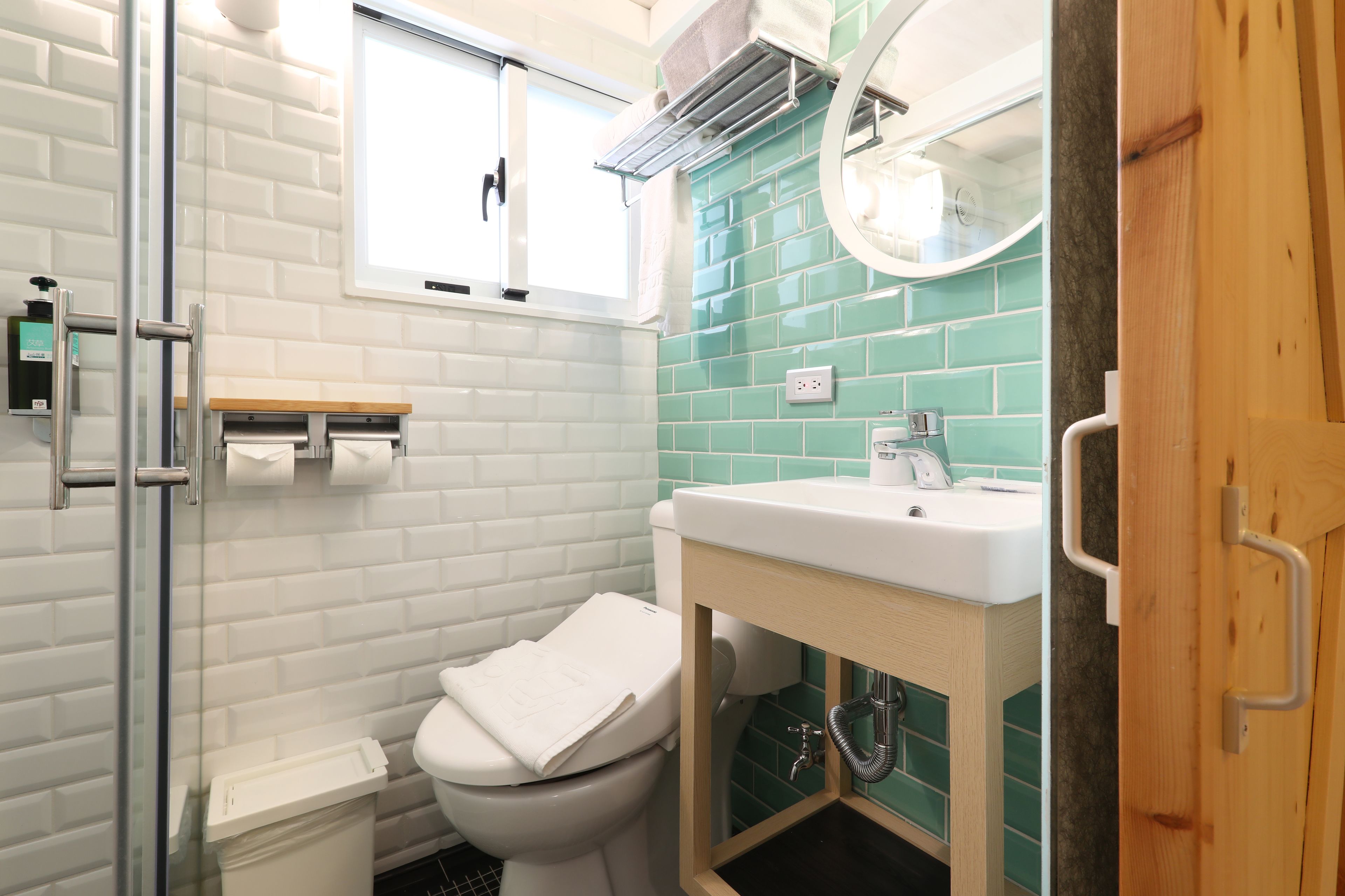 A bathroom with a white toilet, a sink with a mirror, and a shower area.