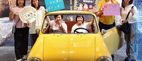 A yellow vintage car with a sign reading "MINI HOTELS" in front.