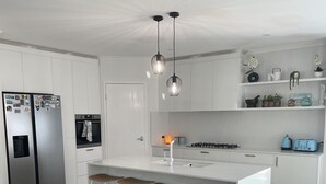 Una cocina moderna con armarios blancos, una isla central con taburetes de bar, horno empotrado y estufa a gas.