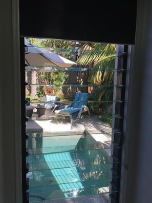 A glass-enclosed outdoor area with a pool, lounge chairs, and umbrellas.