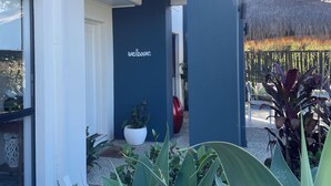 Un edificio moderno con una entrada acogedora, un cartel que dice 'welcome' y vistas a un viñedo al fondo.