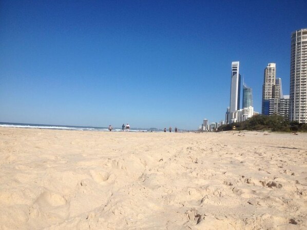 A beach with footprints and a cityscape in the background.
