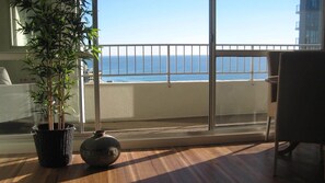 Enjoy the ocean view from this room's large window, featuring a comfortable chair and a potted plant.