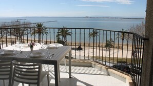 Un balcon avec une table dressée pour le dîner, offrant une vue sur la plage et la mer.