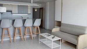 Un salon moderne avec un canapé gris, une table basse et trois tabourets de bar.