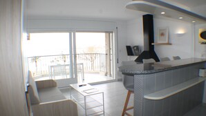 Une cuisine moderne avec un coin bar, un espace repas comprenant une table et des chaises, et une porte-fenêtre coulissante donnant sur un balcon.
