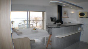 Une cuisine moderne dotée d’un îlot central intégré, d’un coin repas avec une table et des chaises, et offrant une vue sur l’extérieur grâce à une grande porte-fenêtre coulissante.
