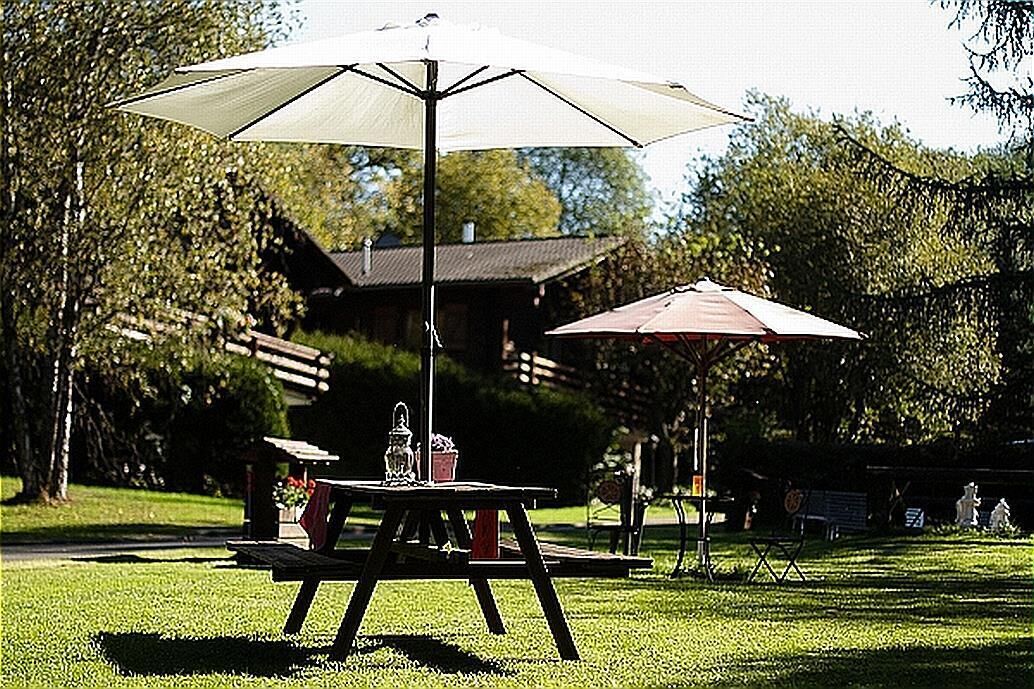 Une table de pique-nique avec un auvent dans un parc, avec un bâtiment en arrière-plan.