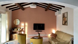 A living room with a sofa, two yellow chairs, a TV, and a painting on the wall.