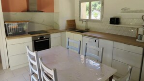 A compact kitchen with a built-in oven, a sink, and a window above it.