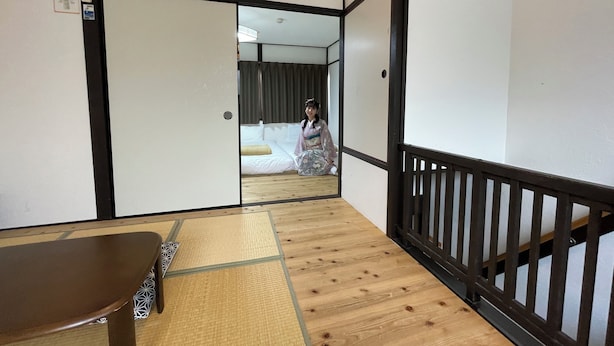 A traditional Japanese room with tatami flooring, sliding doors, and a low wooden railing. - Guest house Connection Karasuma Gojo (Kyoto)