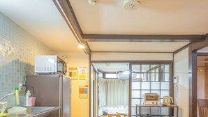 A compact kitchen with a refrigerator, microwave, and a small dining area with a table and chairs. - Guest house Connection Karasuma Gojo (Kyoto)