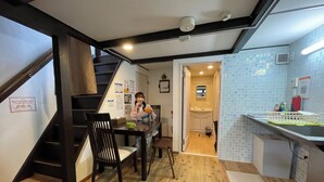 A dining area with wooden flooring, a staircase, and a kitchen with tiled backsplash. - Guest house Connection Karasuma Gojo (Kyoto)