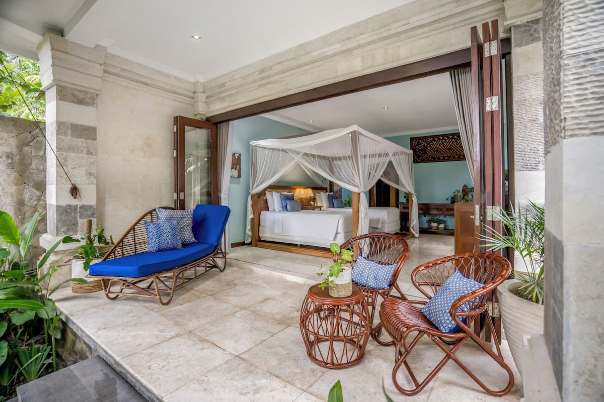 An outdoor seating area with wicker furniture and a canopy bed in the background.