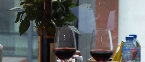 Una mesa con un florero de flores rosas, dos copas de vino, una botella de vino y una botella de agua.