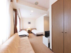 Une chambre d’hôtel avec une armoire en bois, un canapé, deux lits simples, une table de chevet avec une lampe et un téléviseur.