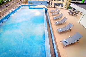 A rooftop swimming pool with a clear blue water surface, surrounded by lounge chairs and a small table. - Bespoke Hotel Puchong (Puchong)