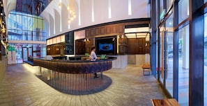 Un moderno vestíbulo con un mostrador de recepción circular central, techos altos y ventanas amplias.