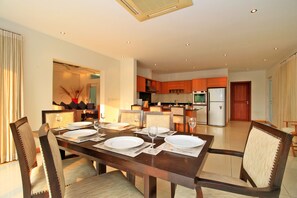 Enjoy meals in this stylish dining area with a long table and matching chairs, surrounded by a clean and minimalist design.
