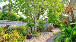 Ein Garten mit Kiesweg, verschiedenen Pflanzen und einem großen Blumentopf.