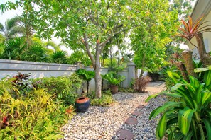 Stroll through the serene garden, lined with lush greenery and vibrant plants, leading to a peaceful entrance.