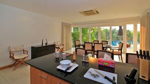 Eine moderne Küche mit Essbereich, großen Fenstern und Blick auf einen Pool.