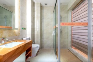 Un baño moderno con tocador de mármol, cabina de ducha de vidrio y retrete.
