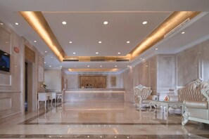 Un hall amplio con piso de mármol, asientos elegantes e iluminación empotrada.