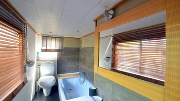 Een bad, een haardroger, handdoeken, toiletpapier