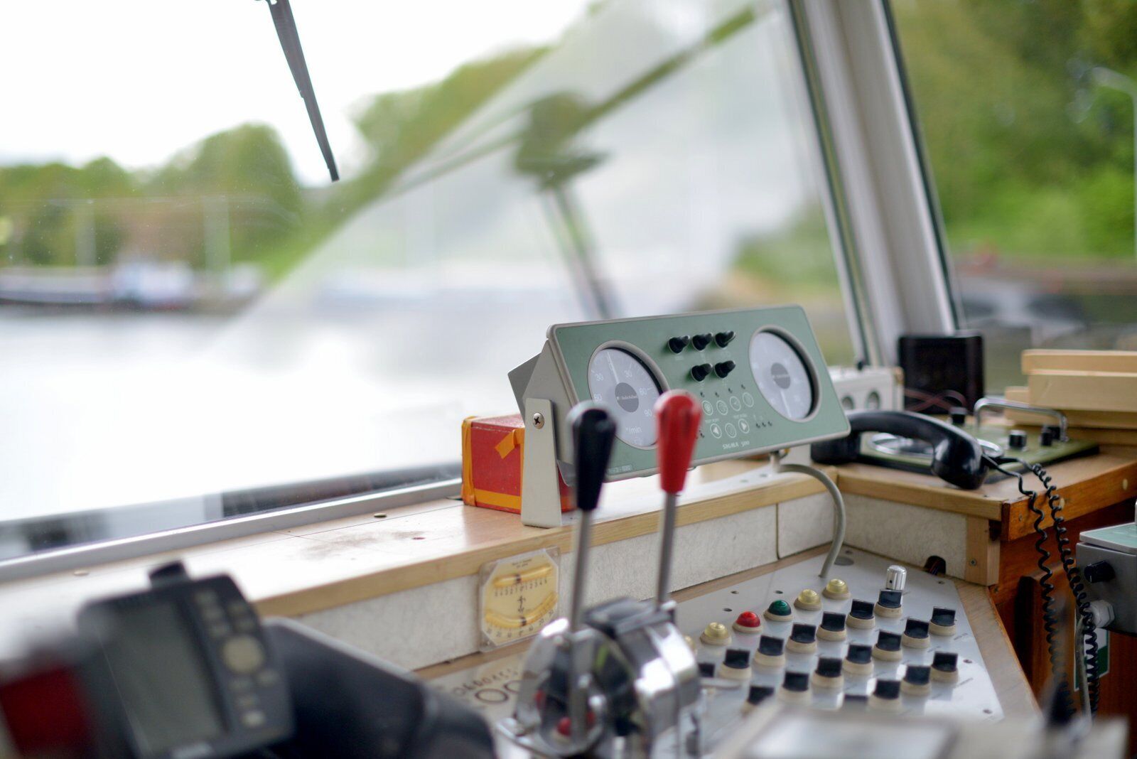 Een bedieningspaneel met meters, een telefoon en diverse schakelaars op het dek van een boot.