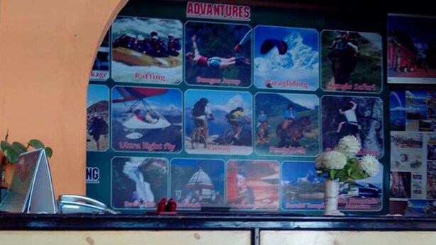 A bar area with a wooden counter, red stools, and a wall decorated with adventure-themed pictures. - Hotel Highland Comfort (Pokhara)