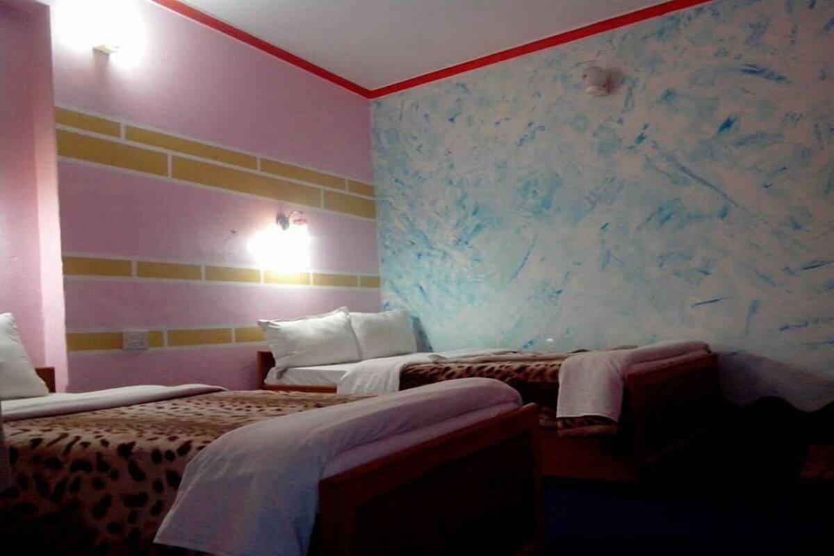 Ein Zimmer mit zwei Betten, einer Wand mit Ziegeloptik und einer blauen Wand mit Struktur.