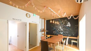 A conference room with a wooden table and chairs, a blackboard with a map, and a sign that reads "Watch out your head". - Kanazawa guesthouse nagonde - Hostel (Kanazawa)