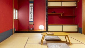 A traditional Japanese room with tatami flooring, a low wooden table, cushions, and a sliding door. - Kanazawa guesthouse nagonde - Hostel (Kanazawa)