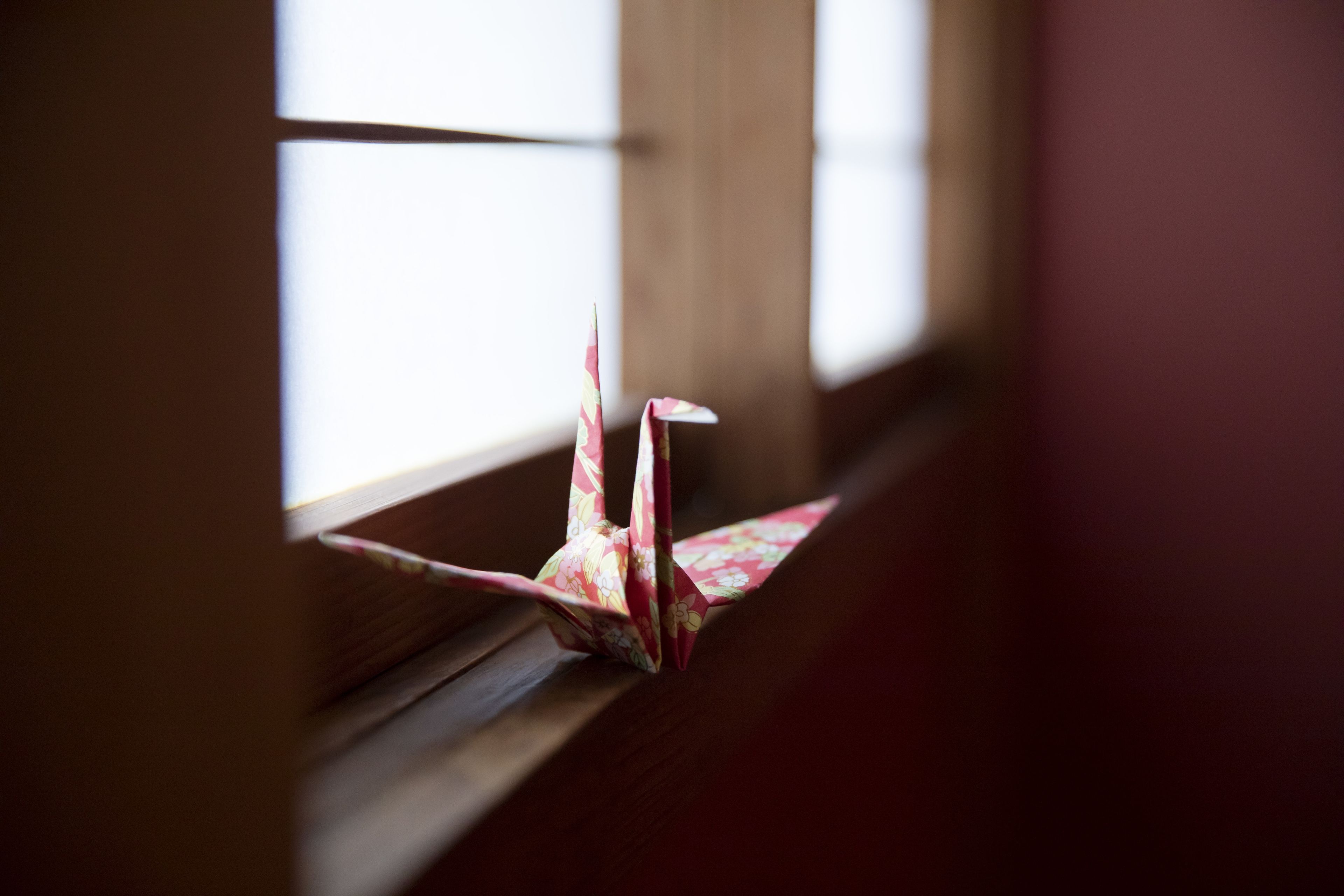 A paper airplane on a wooden ledge.