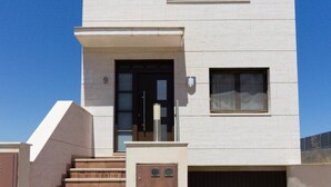 Un bâtiment moderne doté d’un toit plat, d’un escalier menant à une porte et d’une porte de garage.