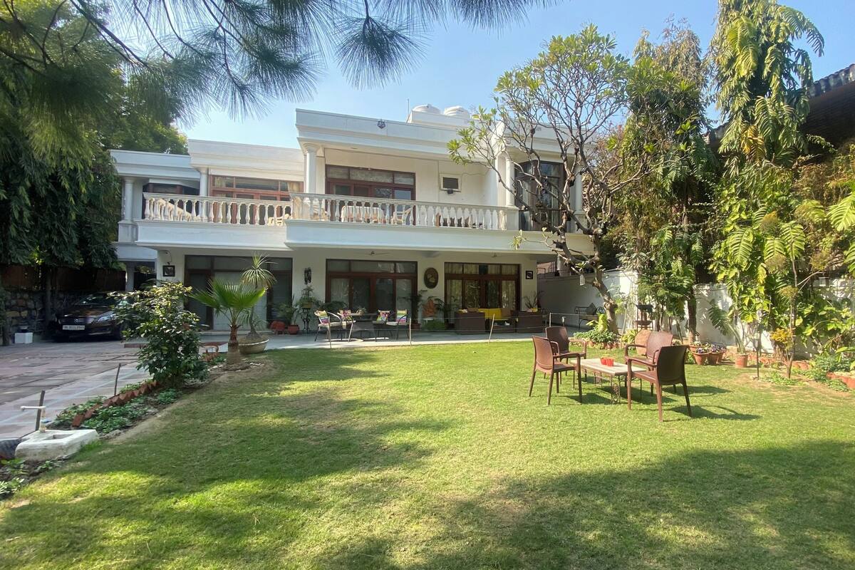 A two-story building with a balcony, a lawn, and outdoor seating.
