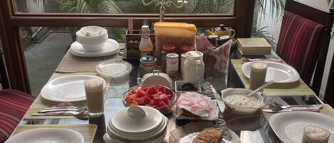 Una mesa de comedor preparada para una comida, con varios platos, bebidas y acompañamientos.