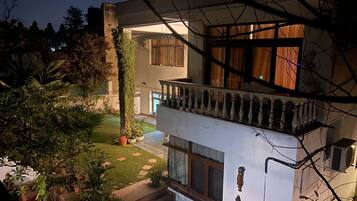A multi-story building with a balcony, potted plants, and a well-maintained lawn.