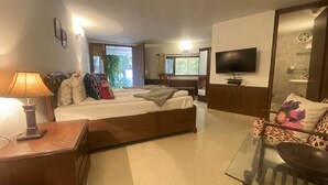 Une chambre d’hôtel avec un lit, un bureau, une chaise, une télévision et une salle de bain visible à travers une porte ouverte.