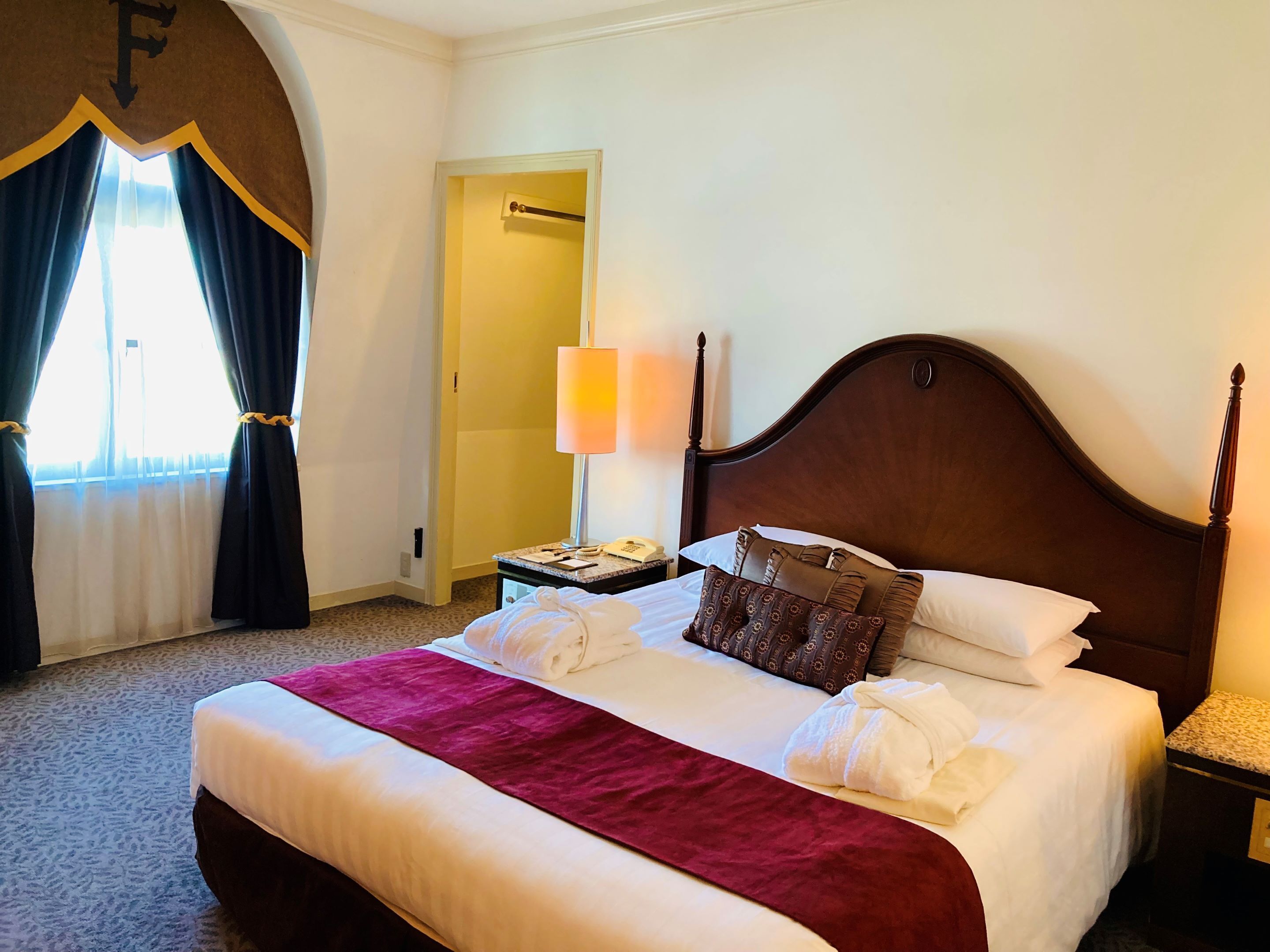 Une chambre d’hôtel avec un grand lit, une table de chevet avec une lampe et une porte donnant sur une autre pièce.
