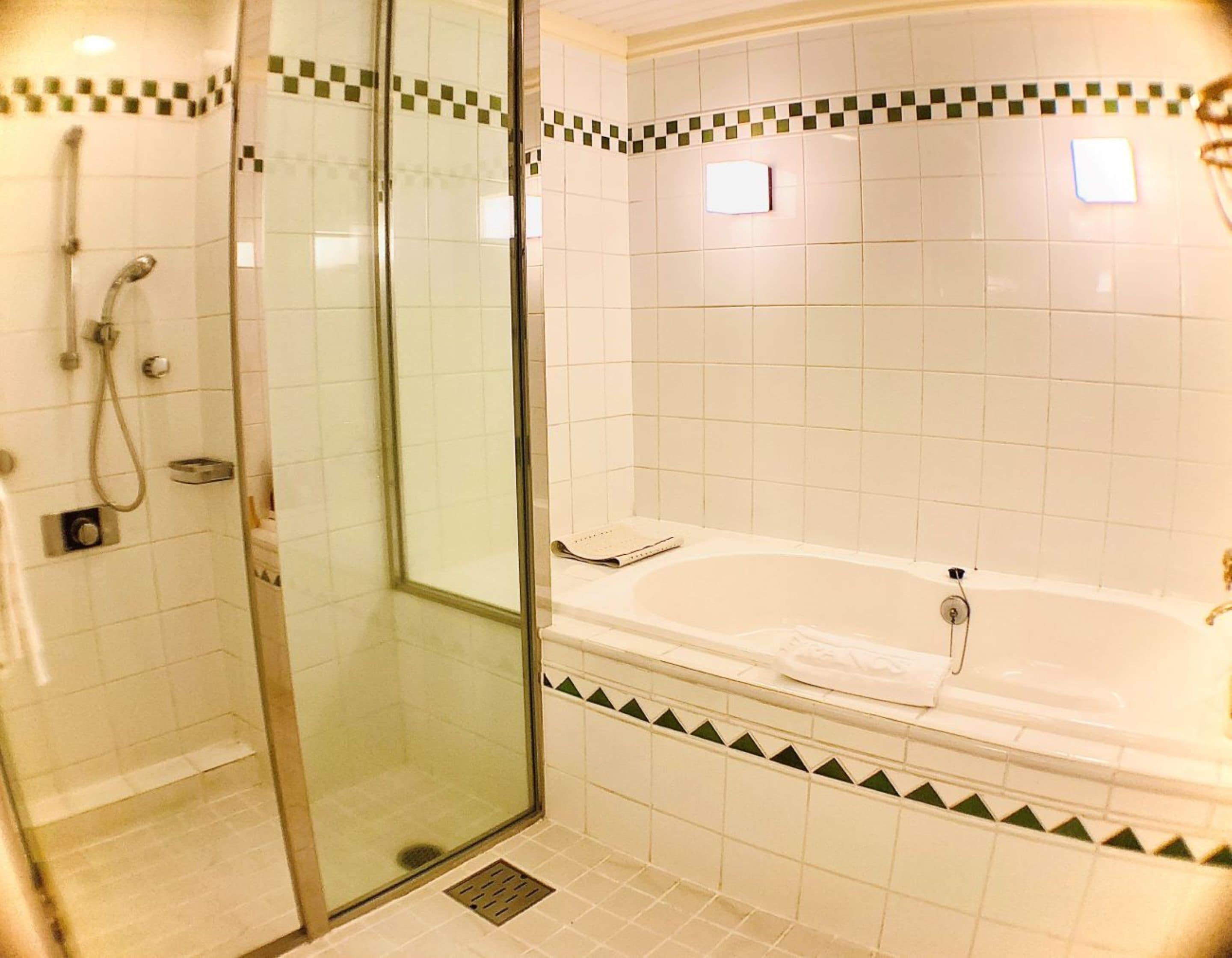Une salle de bain avec une douche à parois de verre, une baignoire et des murs carrelés.
