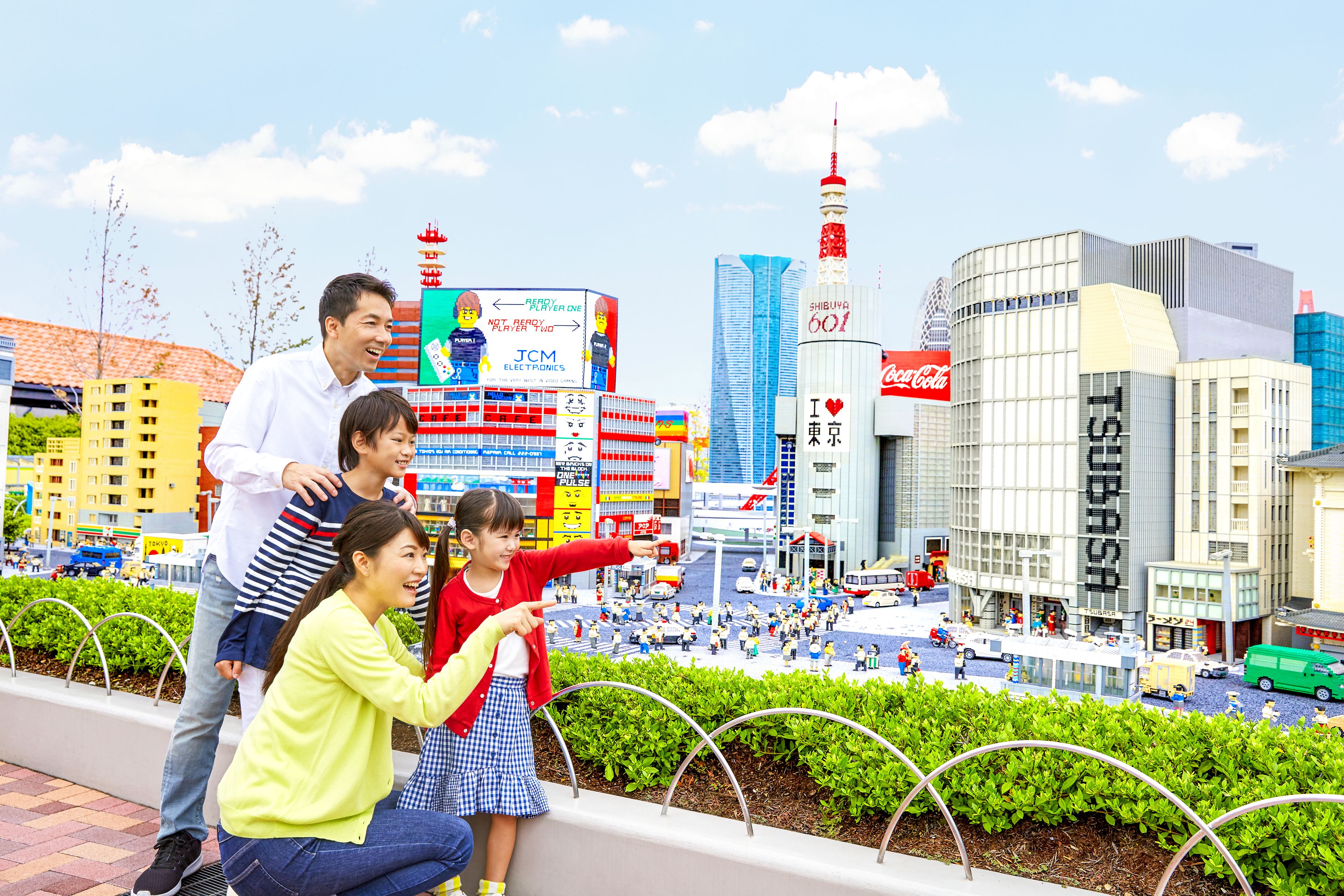 Una vivace scena urbana con edifici moderni, una torre importante e un cartello Coca-Cola.