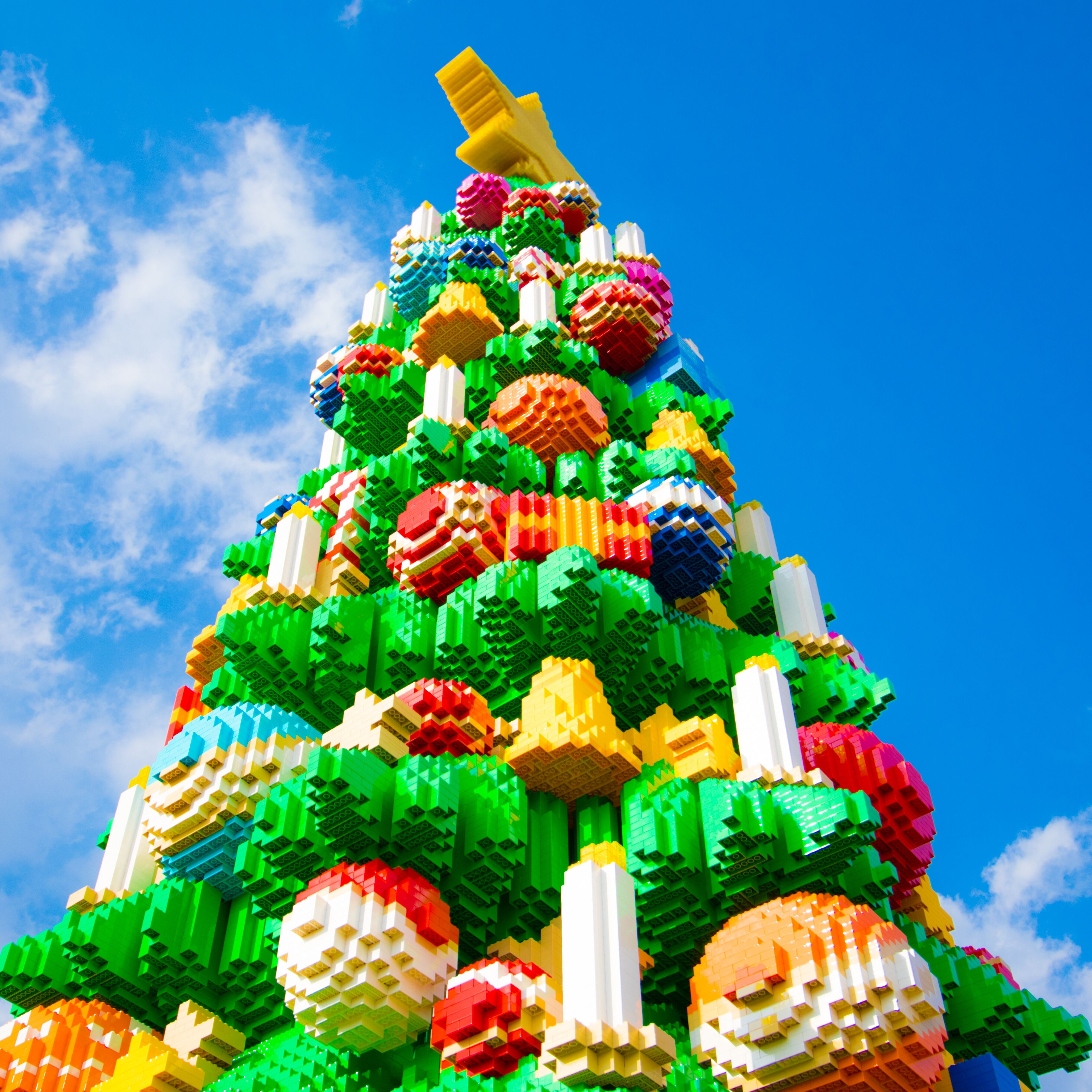 A colorful LEGO Christmas tree with a star on top, set against a blue sky.