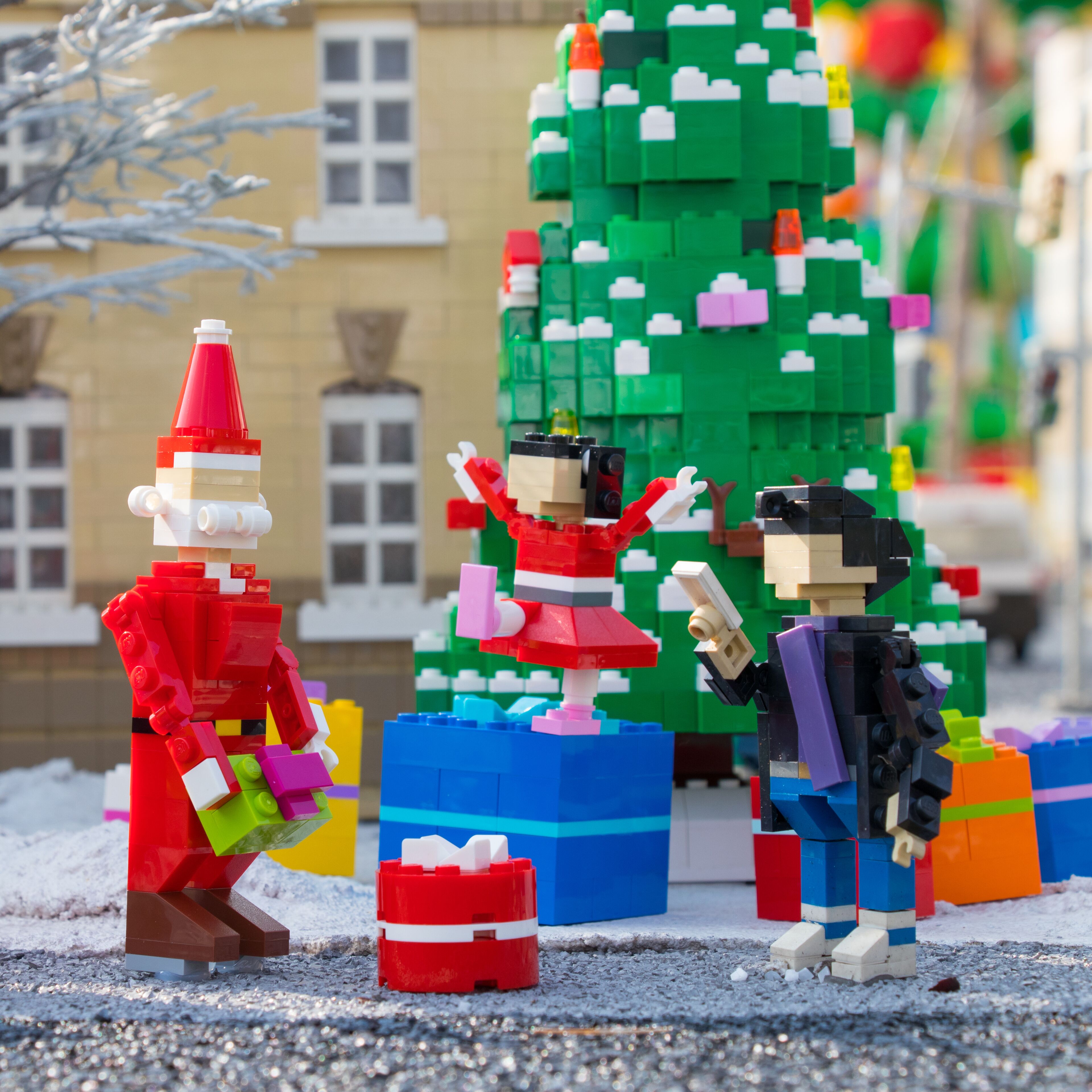 Een LEGO-scène met een kerstboom, cadeaus en LEGO-figuurtjes.