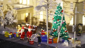A LEGO scene with a large Christmas tree, figures of Santa Claus, and gift boxes.