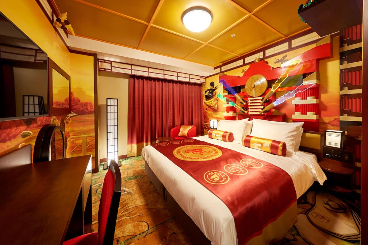 A hotel room with a large bed, a dining table, and a TV.