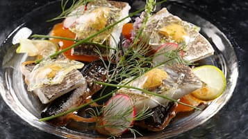 A dish of fish with herbs and lemon slices on a plate.